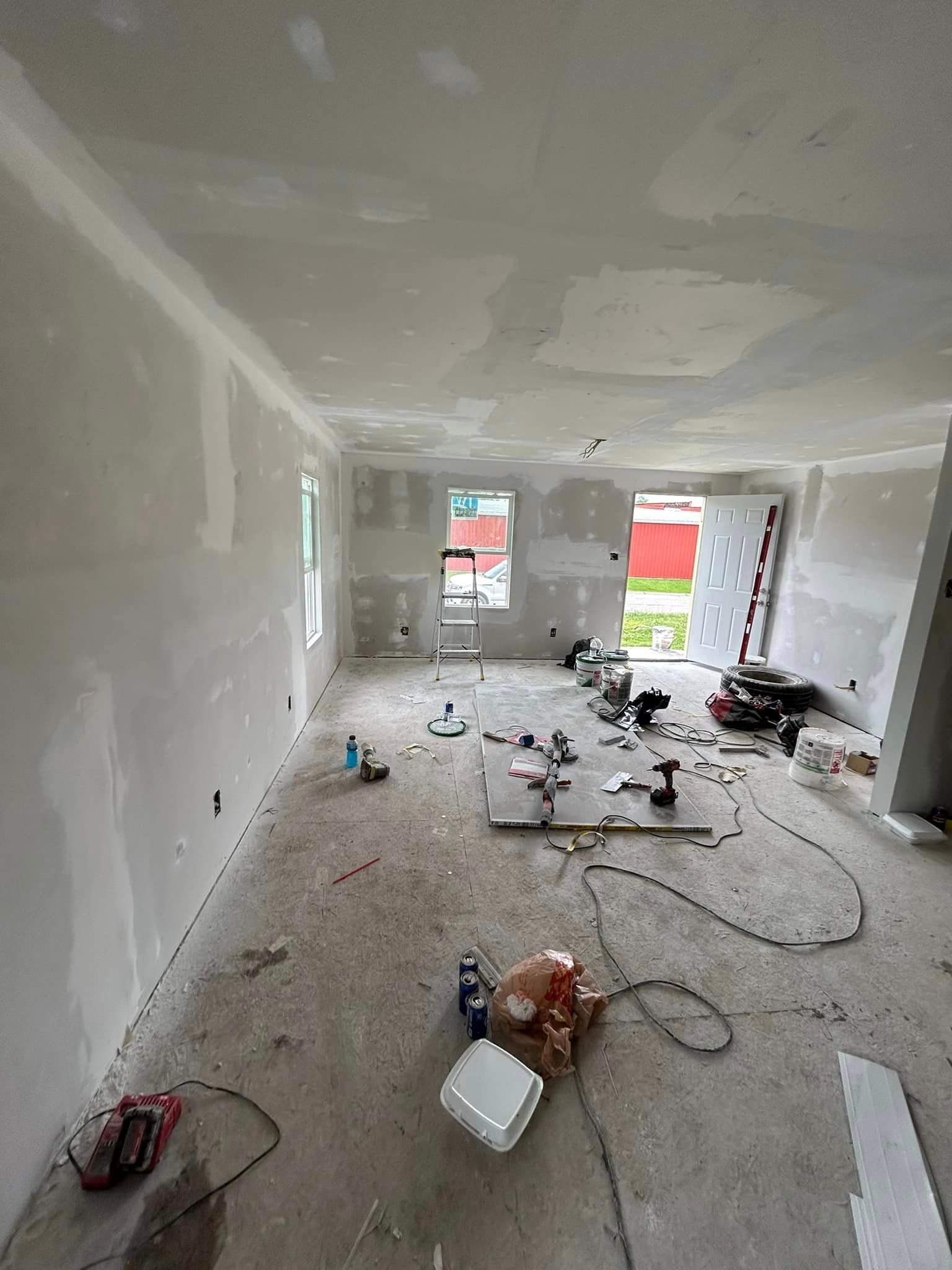 A large room with a lot of tools on the floor is being remodeled.