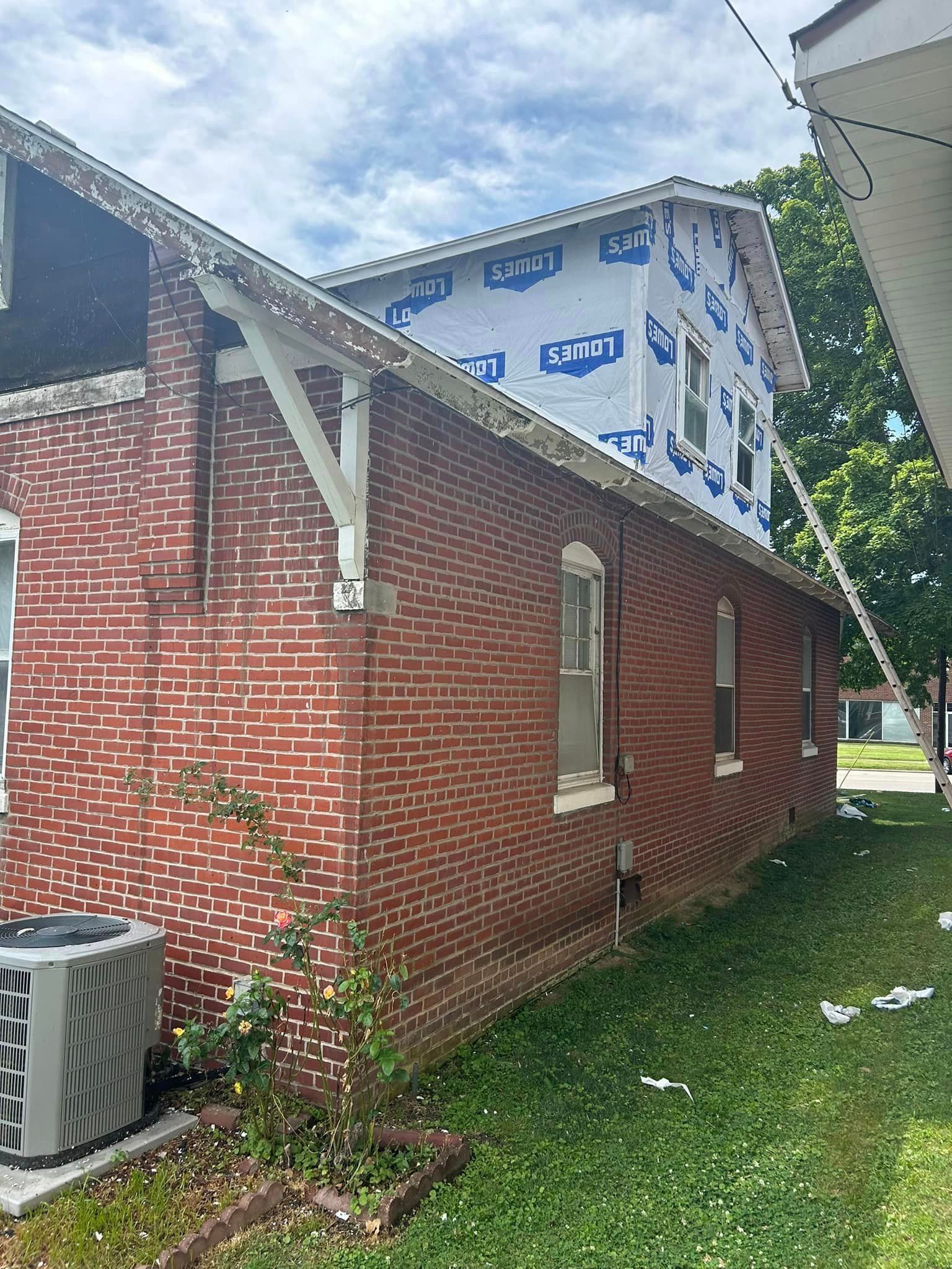 A brick house with a roof that is being remodeled.