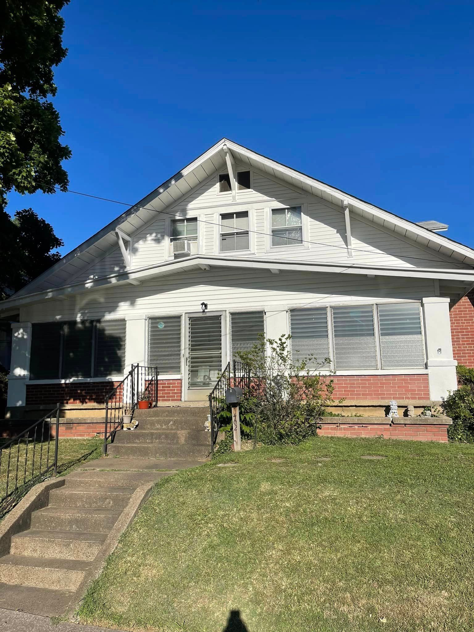A white house with a red brick building and a blue sky in the background.