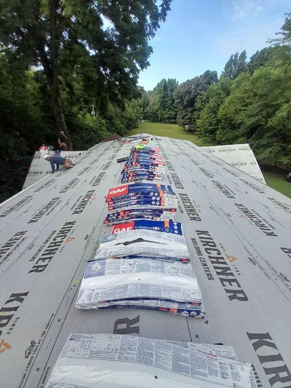 A roof with a lot of shingles on it and trees in the background.