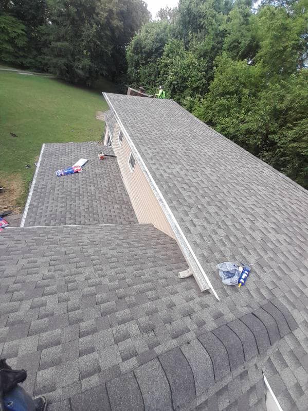 A man is sitting on the roof of a house.