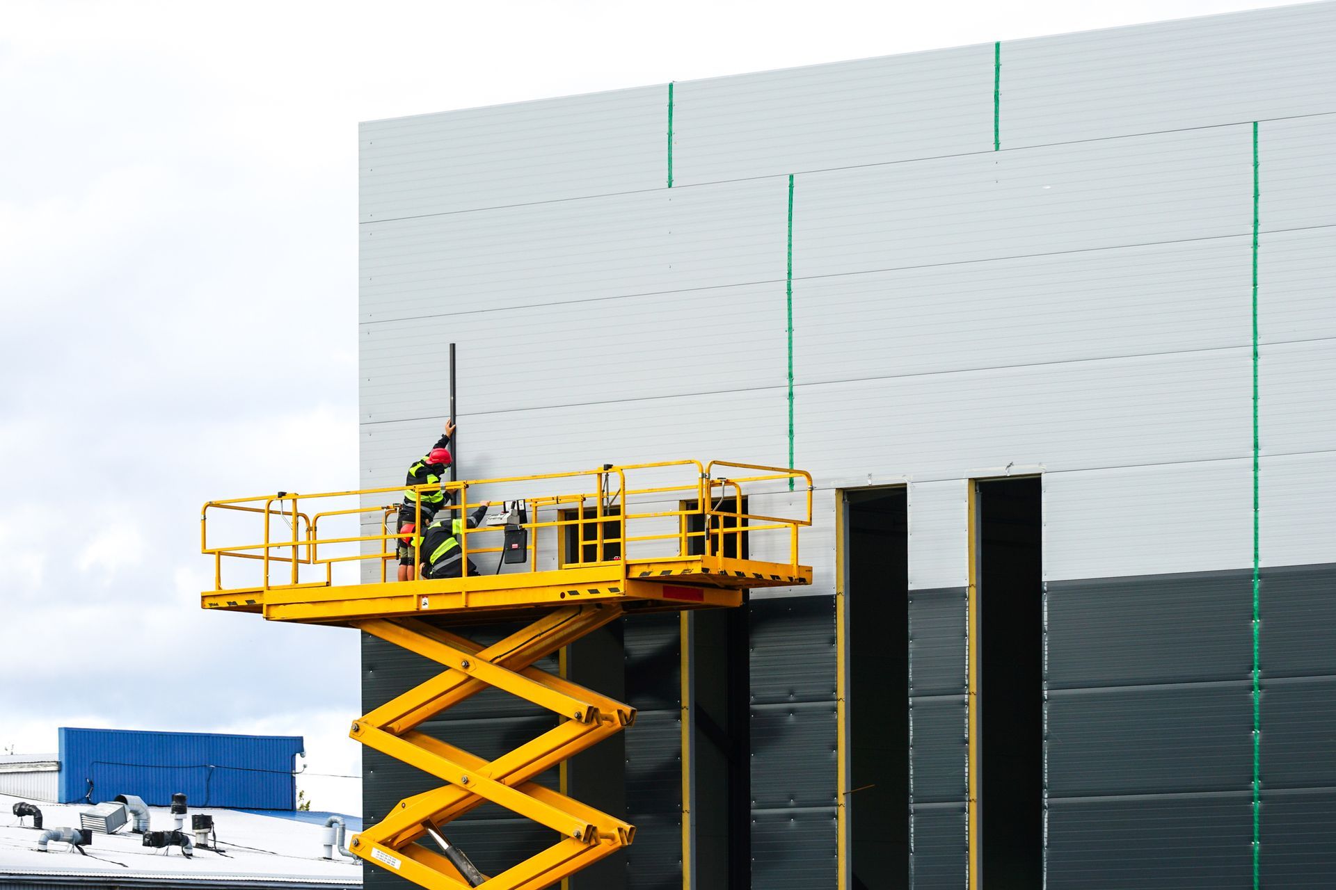 A large yellow self-propelled scissor lift platform with workers.