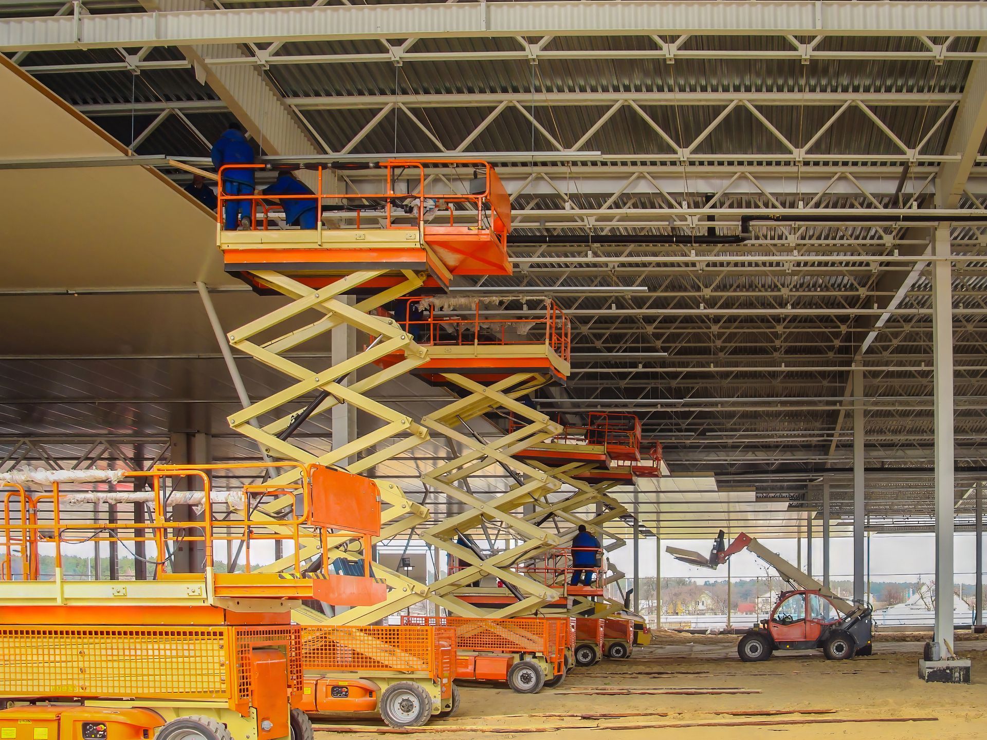 Construction workers installing sandwich panels on a steel frame using scissor lifts. Construction workers installing sandwich panels on a steel frame using scissor lifts.