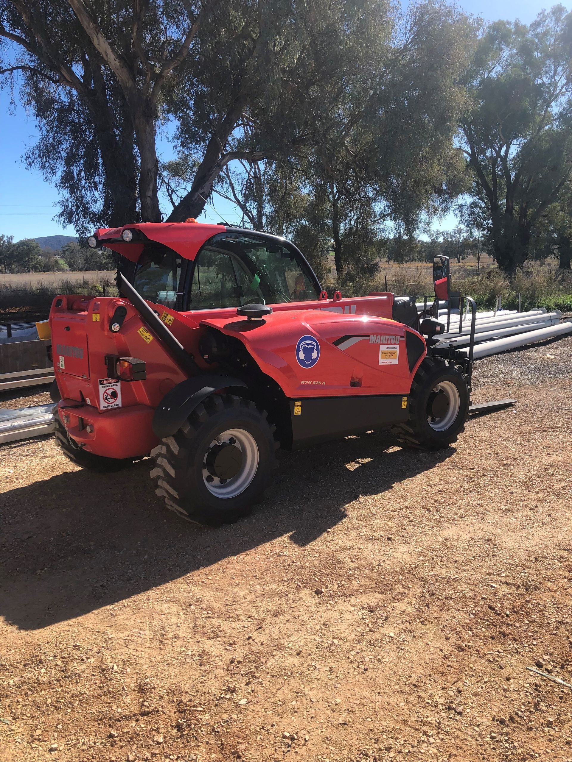 A red forklift is parked in a dirt lot.
