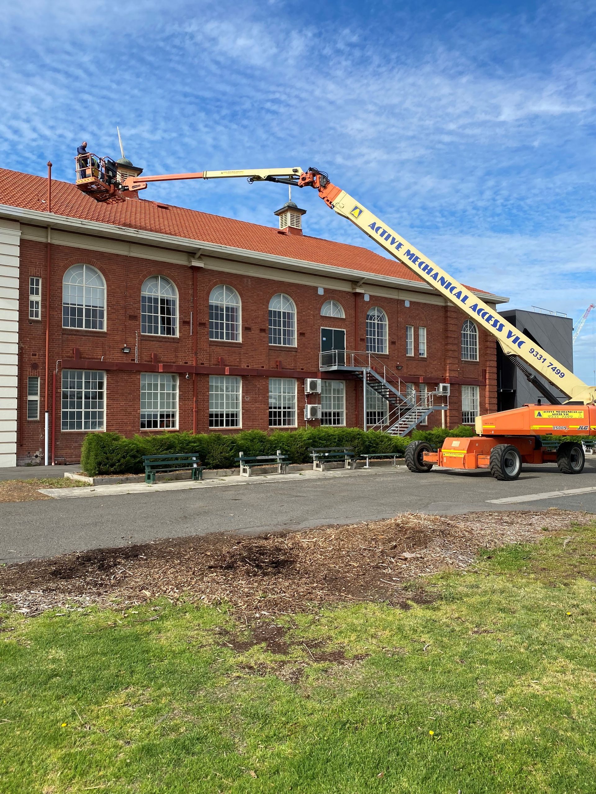 A crane is working on the roof of a brick building.