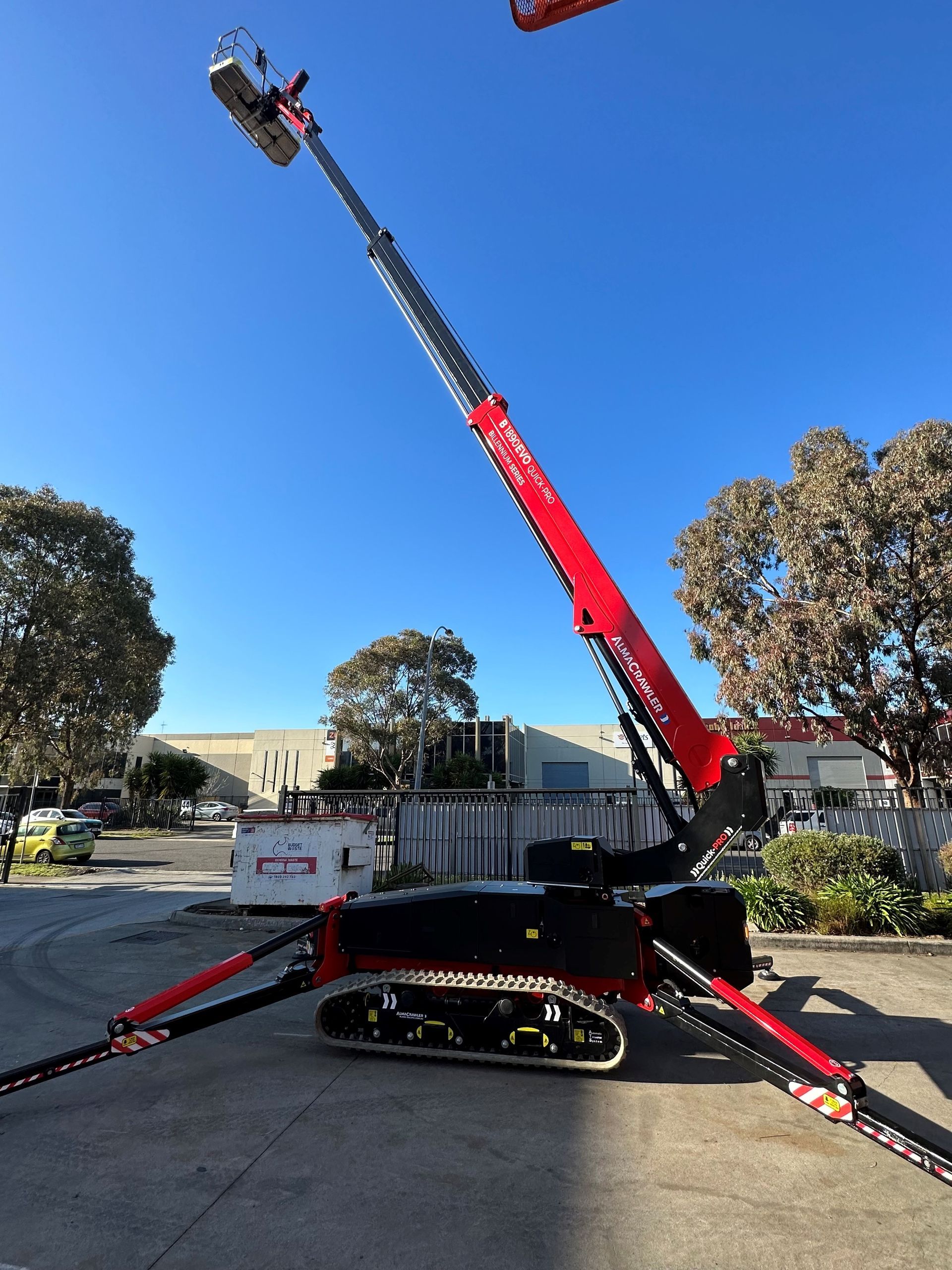 A red and black crane is parked in a parking lot.