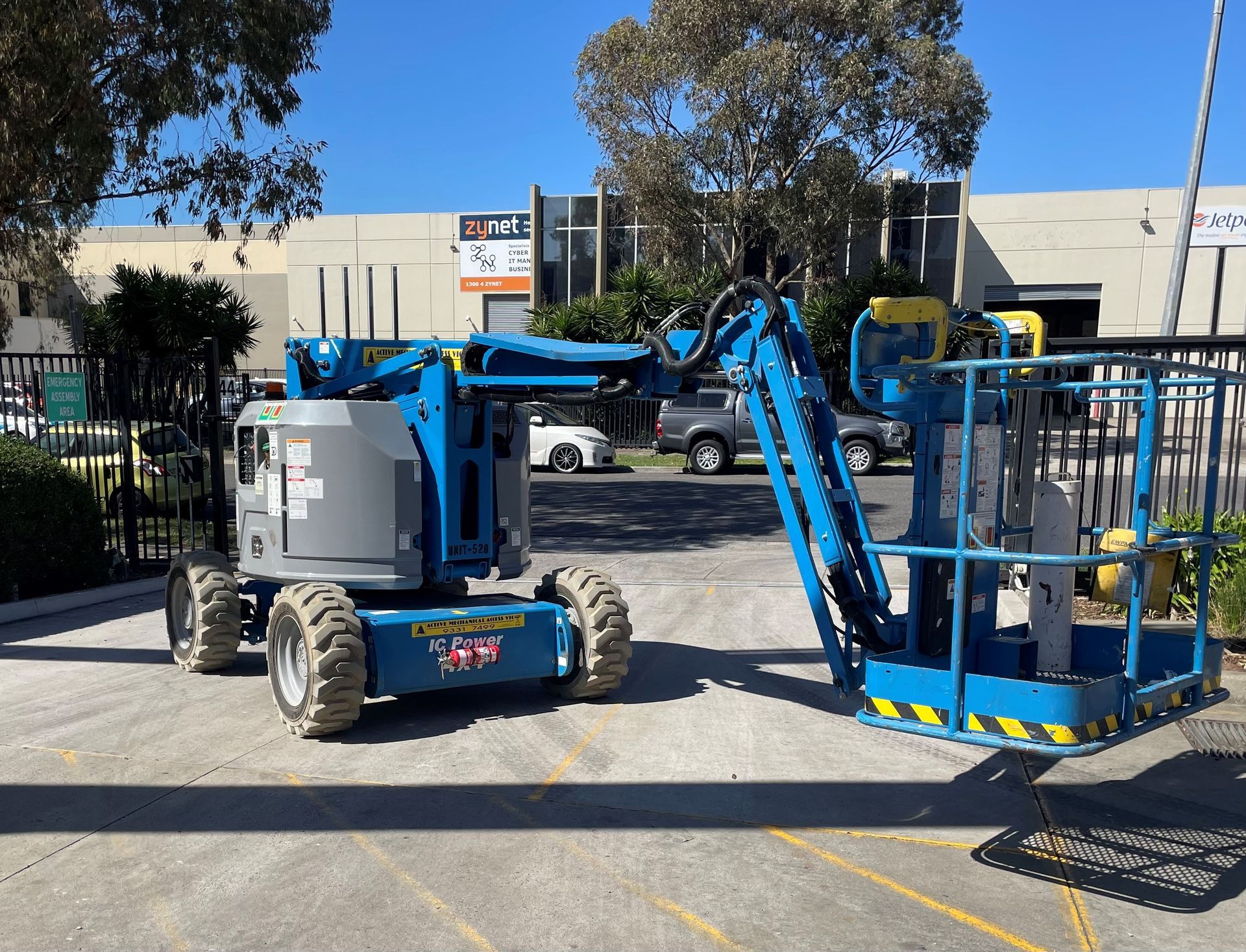 A blue bucket lift is parked in a parking lot