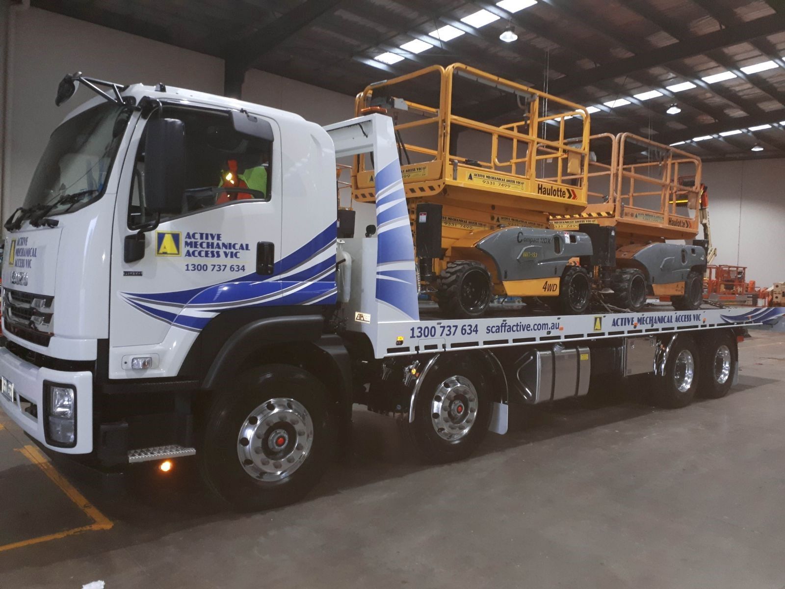 Two orange scissor lifts are parked next to each other