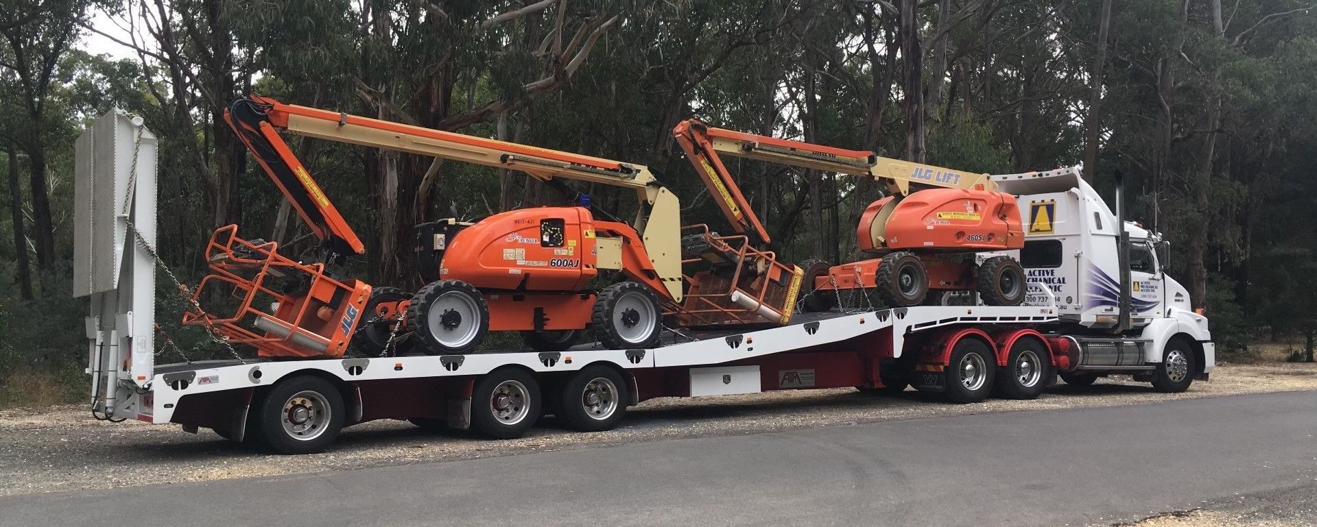 A tow truck is carrying a bunch of heavy machinery on a trailer.