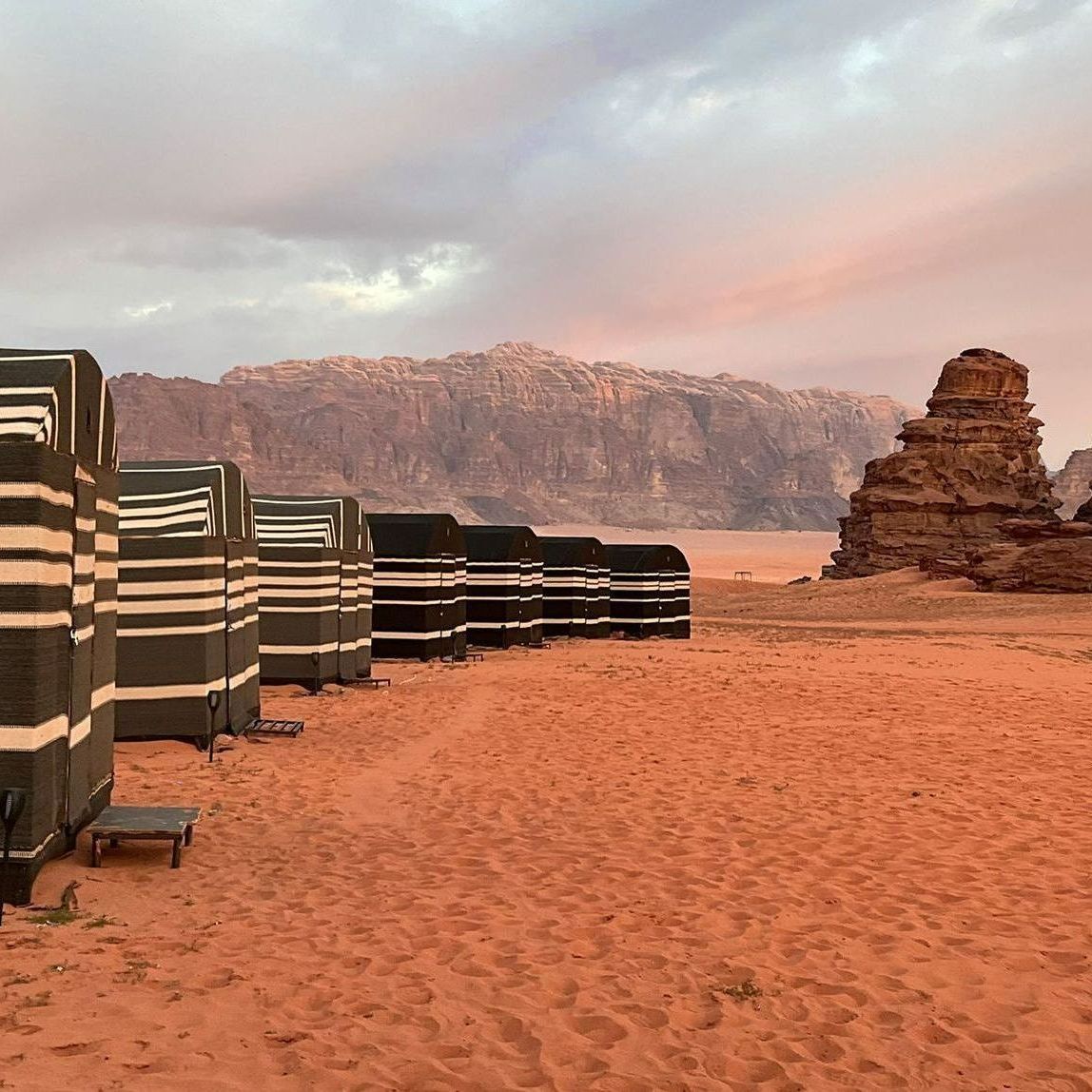 A row of tents in Wadi Rum with mountains in the background.