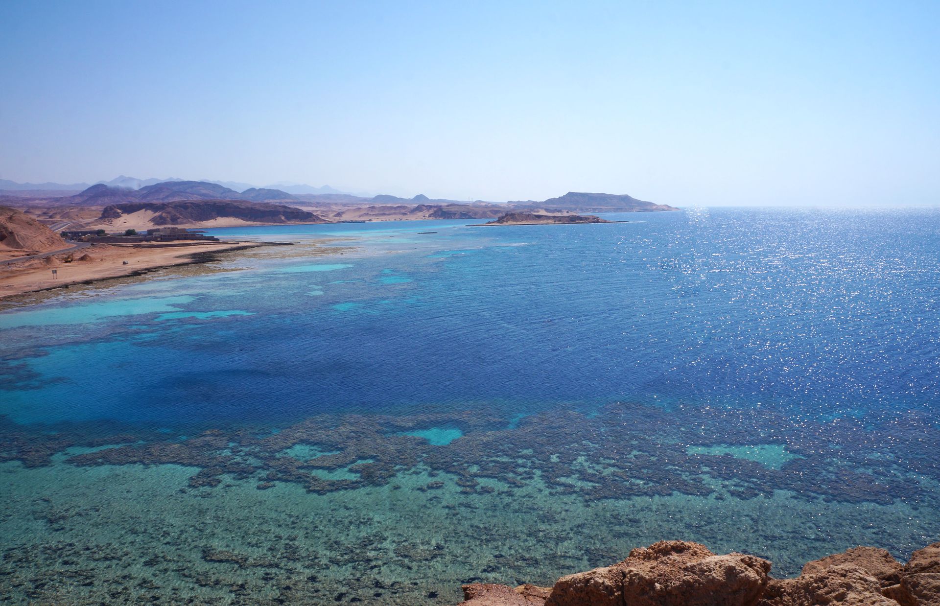 The Sea of Aqaba with mountains in the background and a coral reef in the foreground.