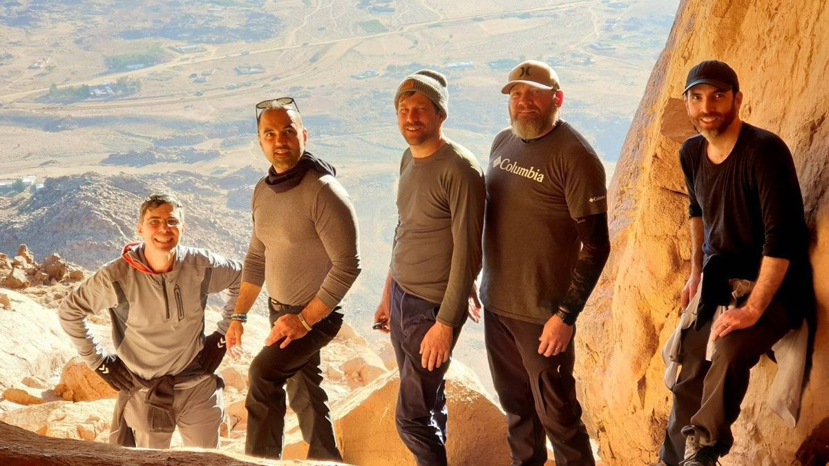 A group of men are standing next to each other on top of a mountain by the Cave of Elijah