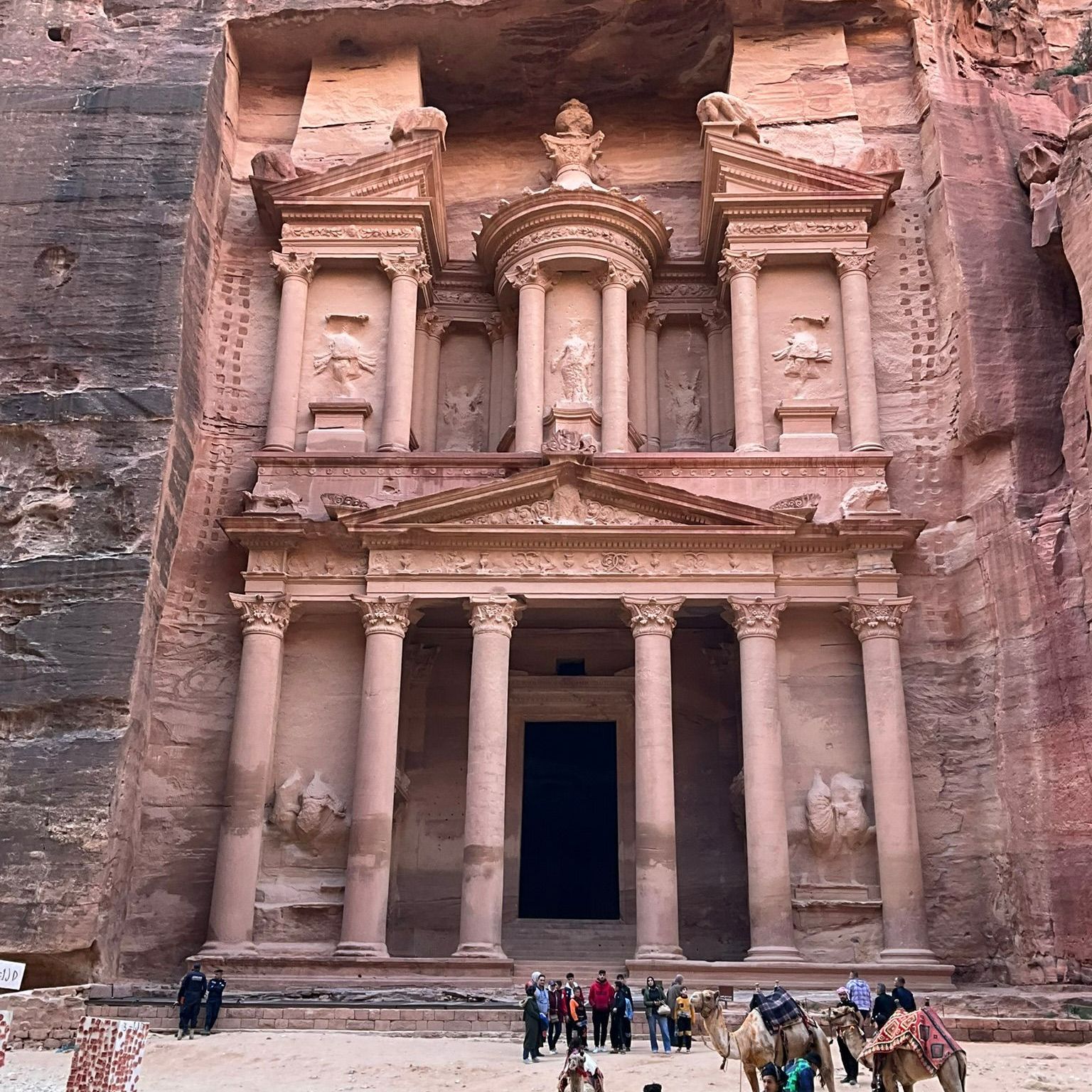 A group of people are standing in front of the Treasury in Petra