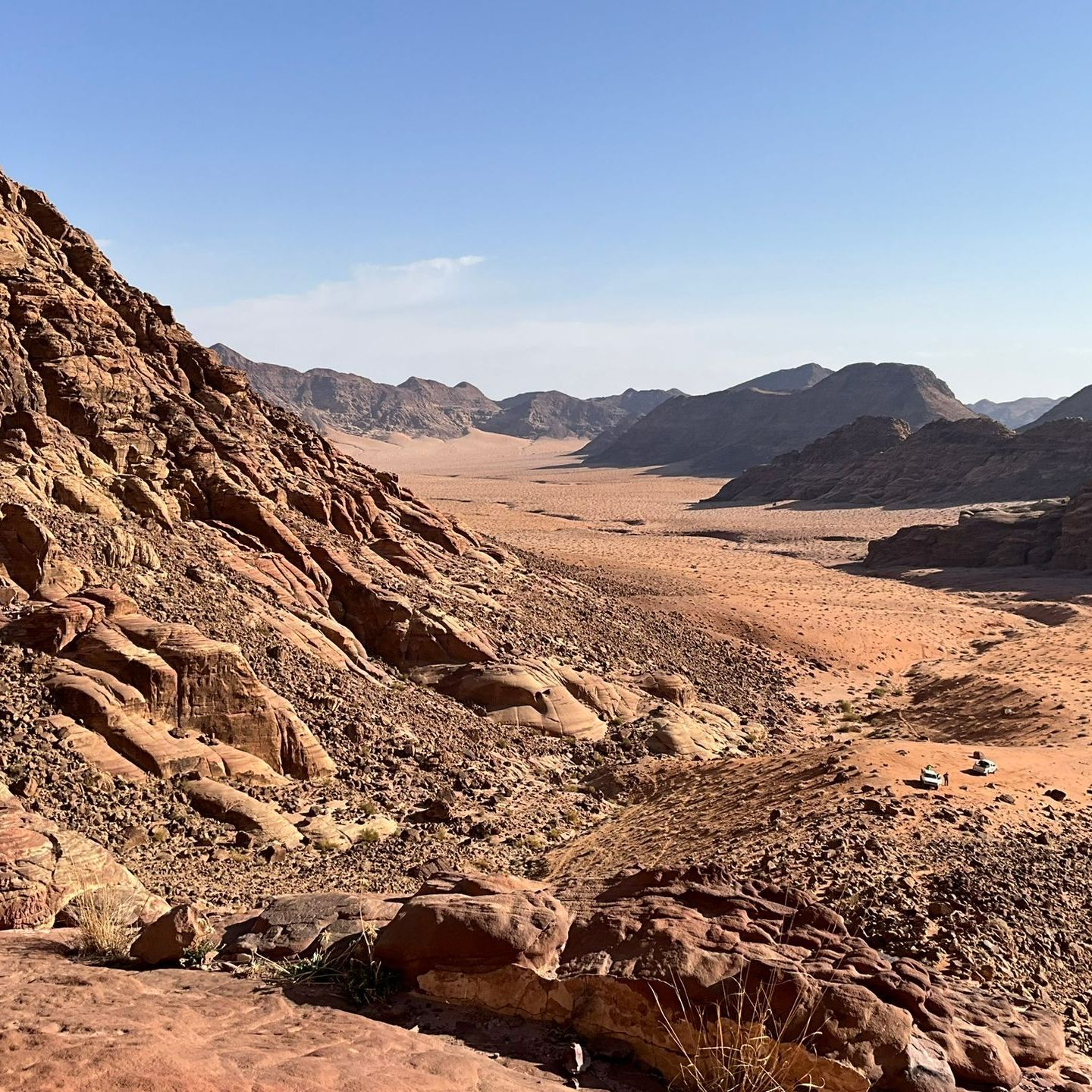 A desert landscape with rocks and Jabal Umm ad Dami in the foreground