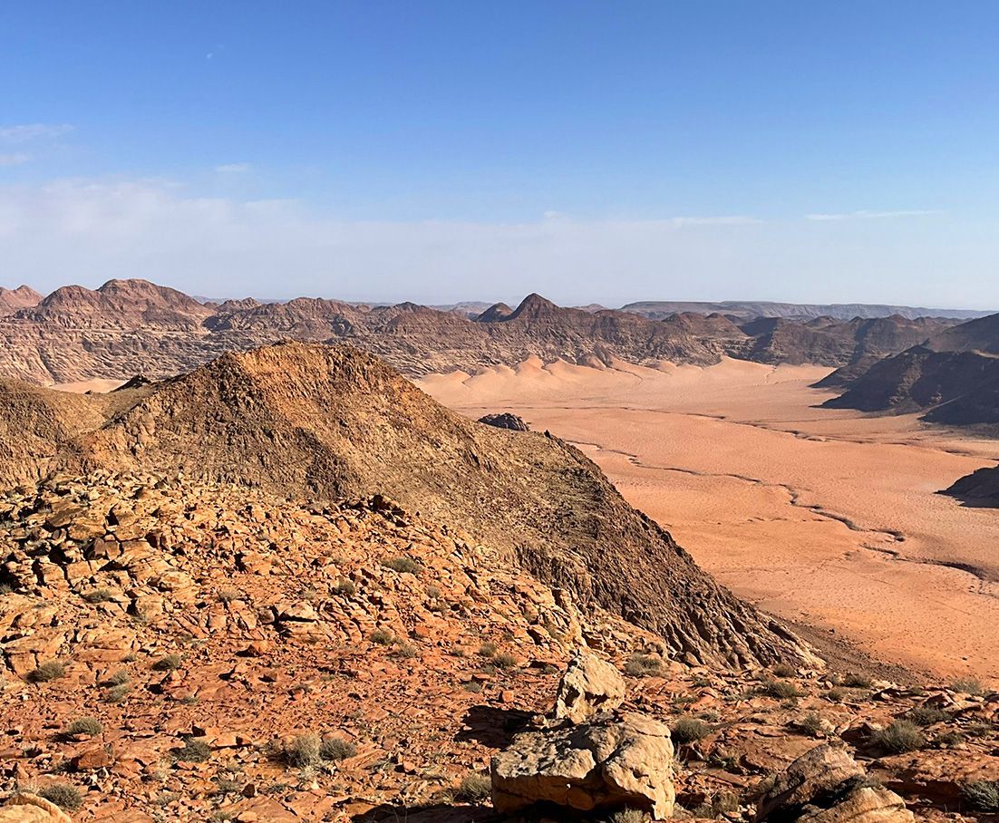 A desert landscape at Wadi Rum with mountains in the background and a blue sky