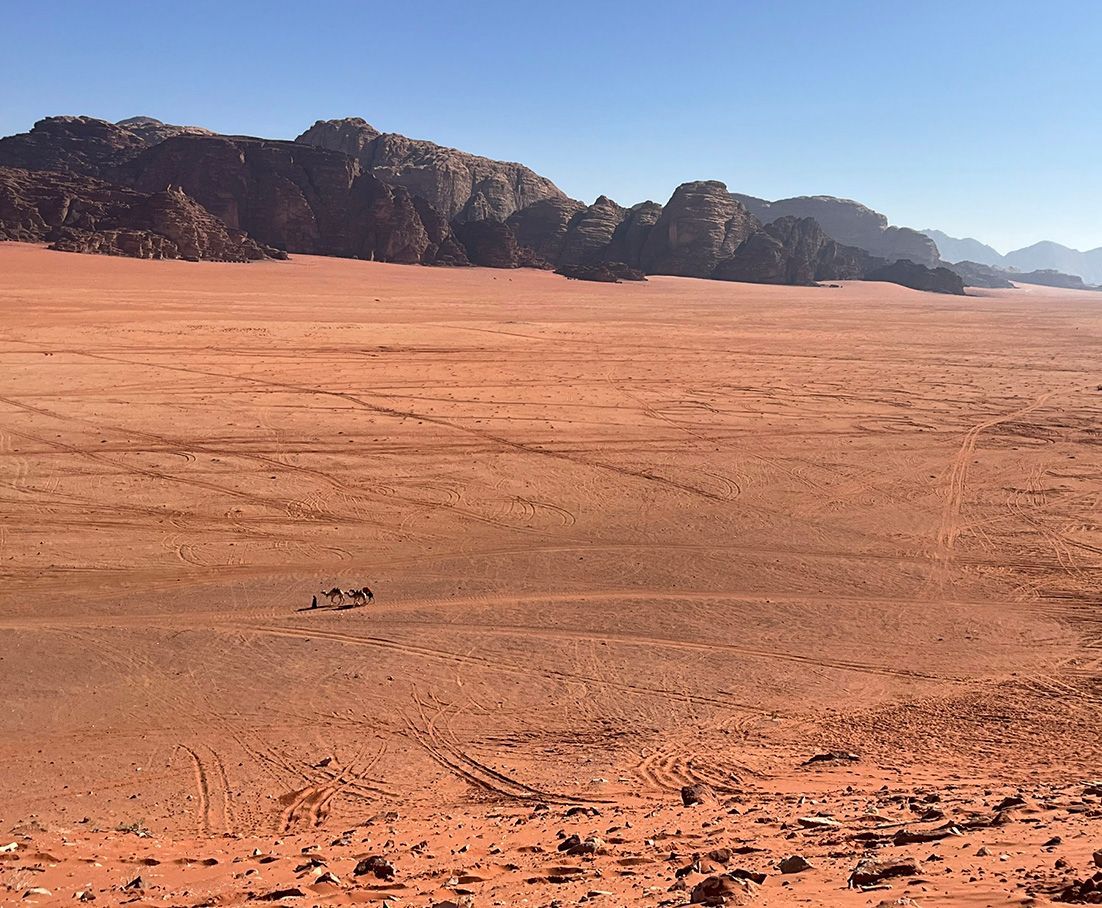 A desert landscape at Wadi Rum with mountains in the background and a blue sky