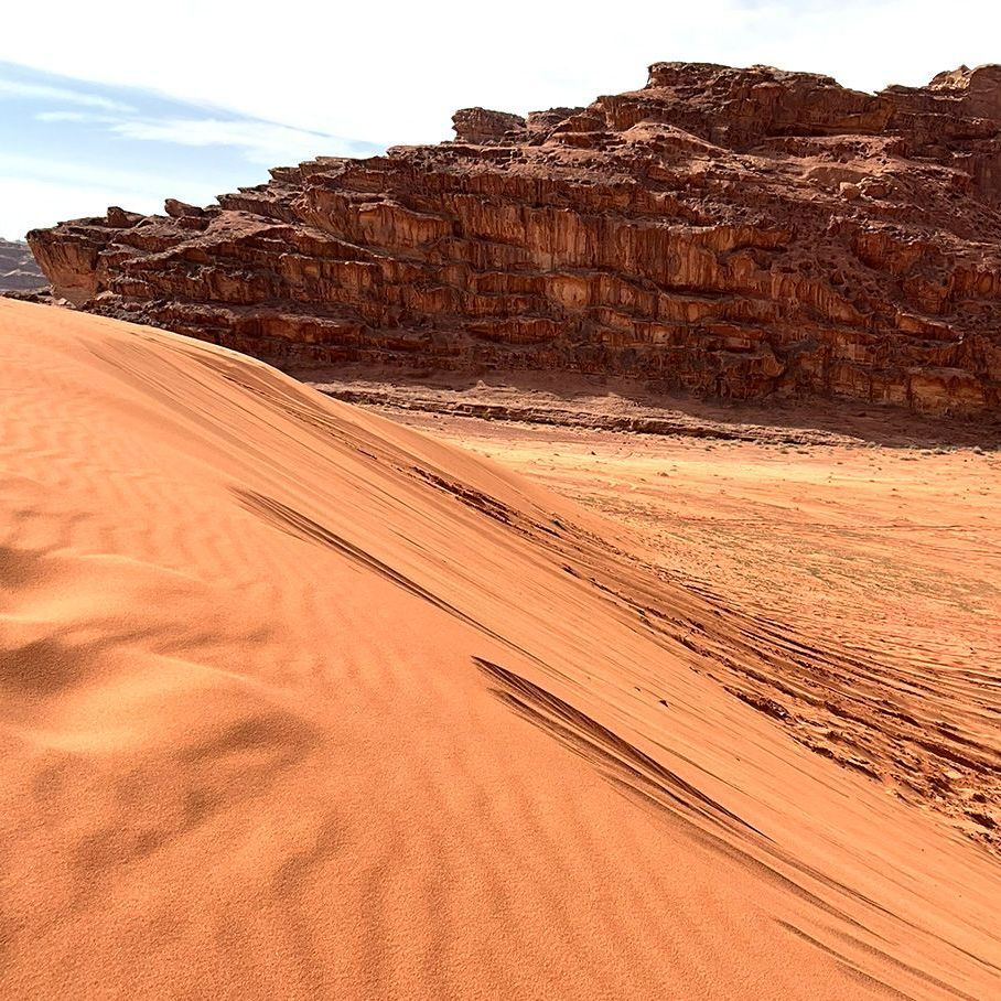 A sand dune in the Wadi Rum Desert with rocks in the background