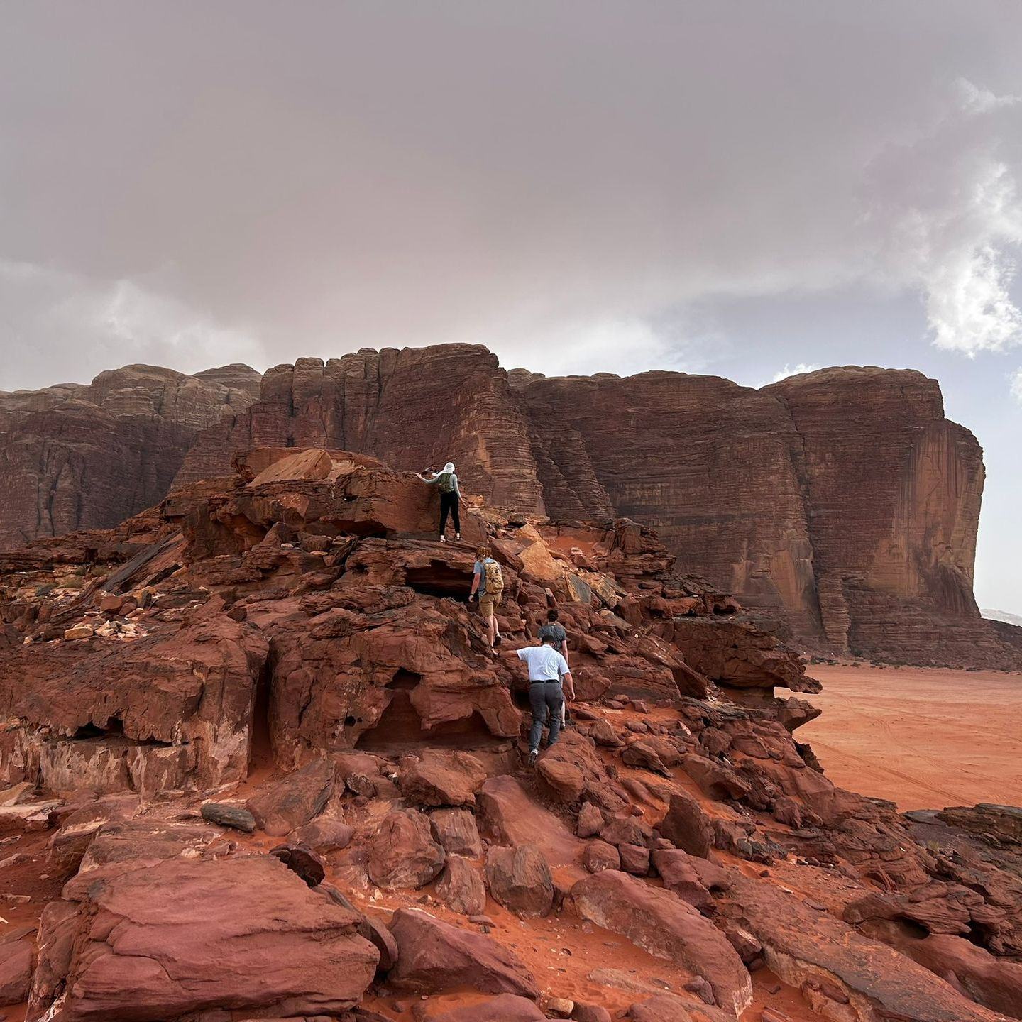 A group of people are walking up a rocky hillside in Wadi Rum