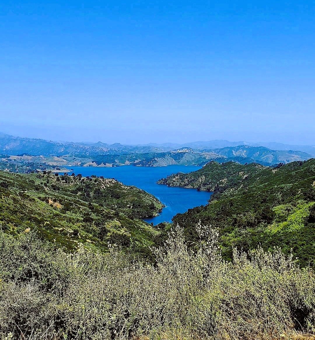 Blue lake between green hills under a clear sky