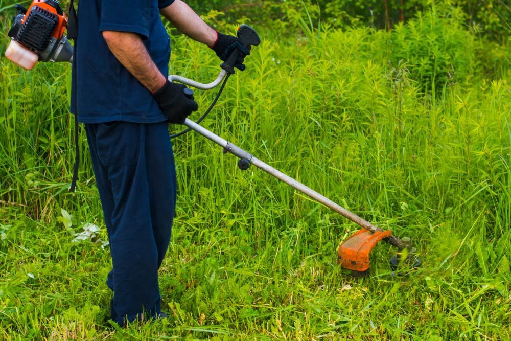 A Man Is Using A Lawn Mower To Cut Grass In A Field — Darren's Mowing In Miranda, NSW