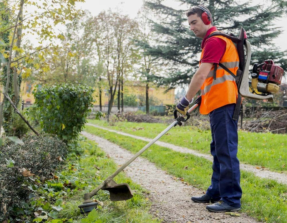 A Man Is Using A Lawn Mower On A Path In A Park — Darren's Mowing In Bowral, NSW