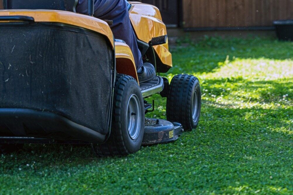 A Man Is Riding A Lawn Mower On A Lush Green Lawn — Darren's Mowing In Hill Top, NSW