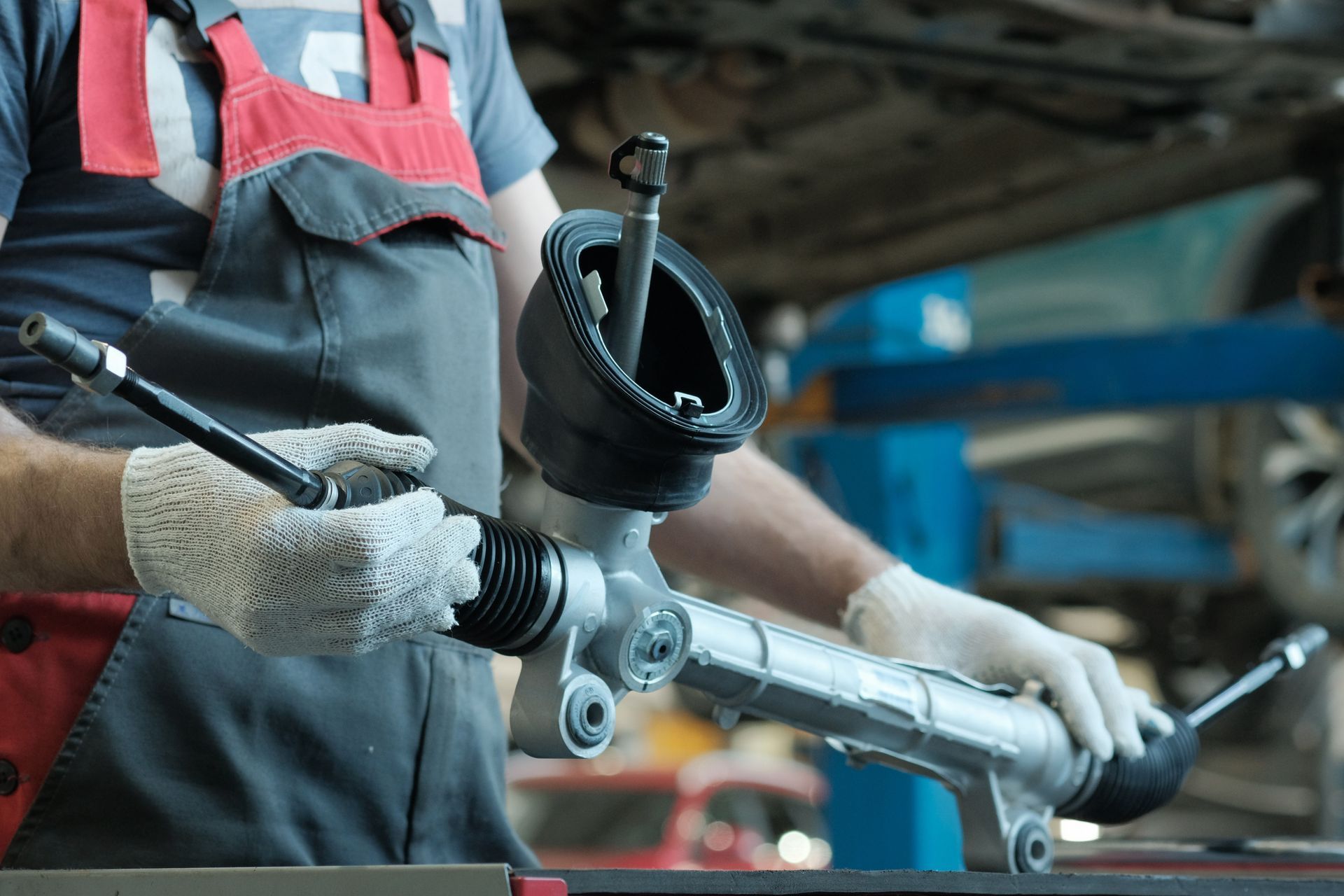 Mechanic holding a car steering rack with gloves on, in a repair shop | Klein Automotive Repair