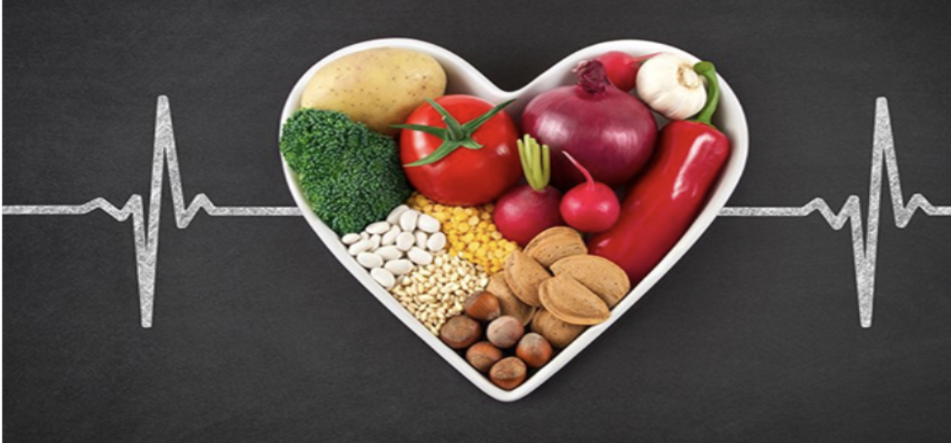 A heart shaped bowl filled with vegetables and nuts.