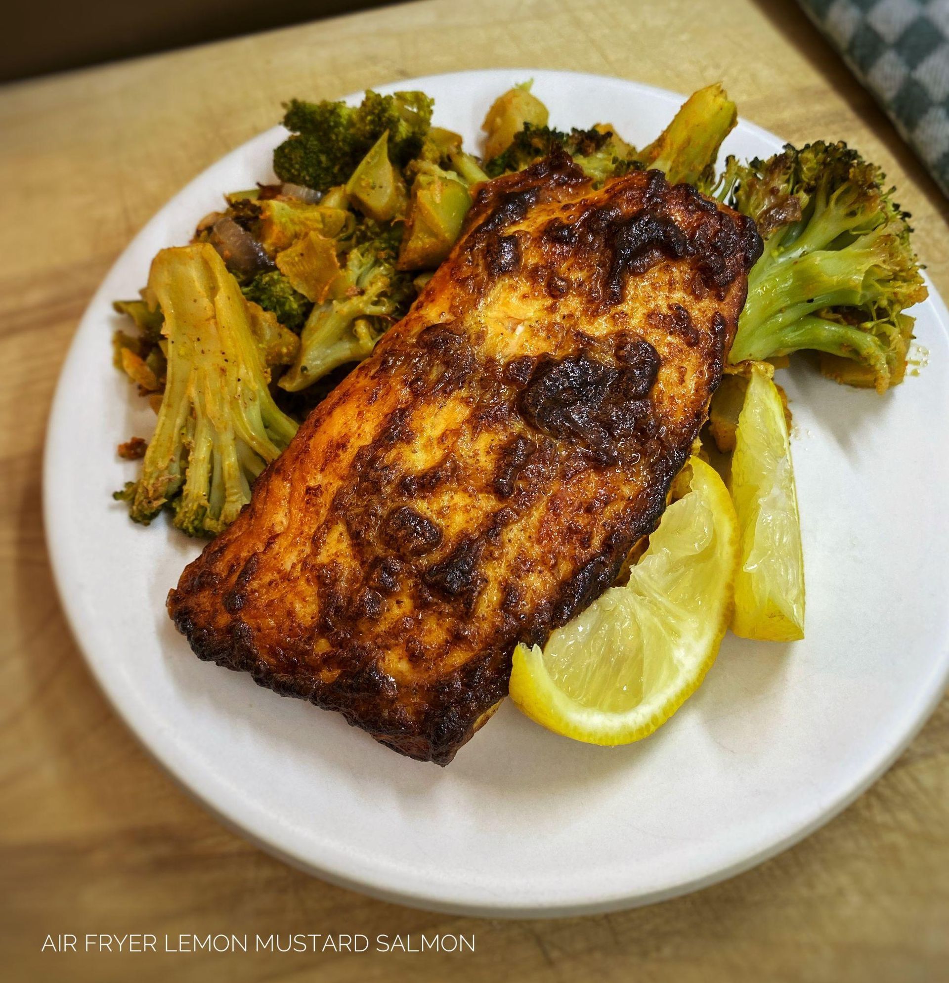 A serving of Air Fryer Lemon Mustard Salmon on a white plate, accompanied by roasted broccoli and le