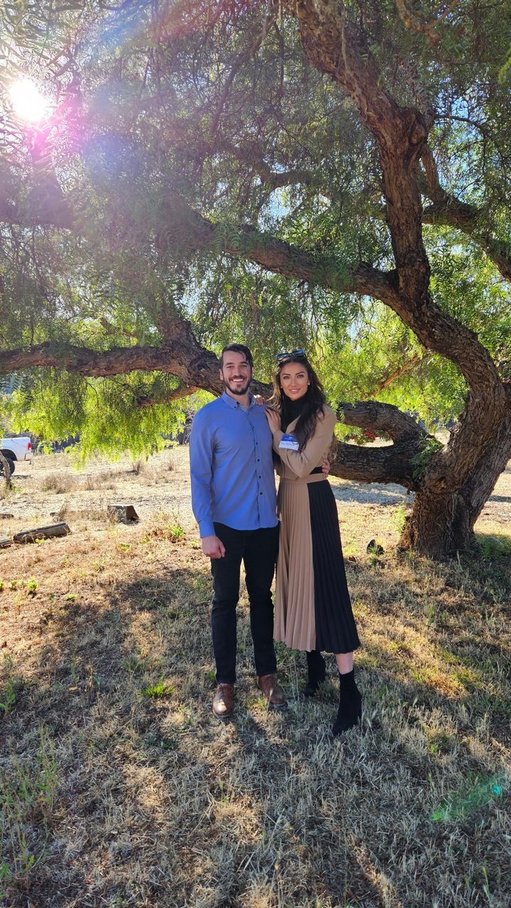 a man and a woman are standing under a tree in a field at a cryotherapy event called the cryo ranch 
