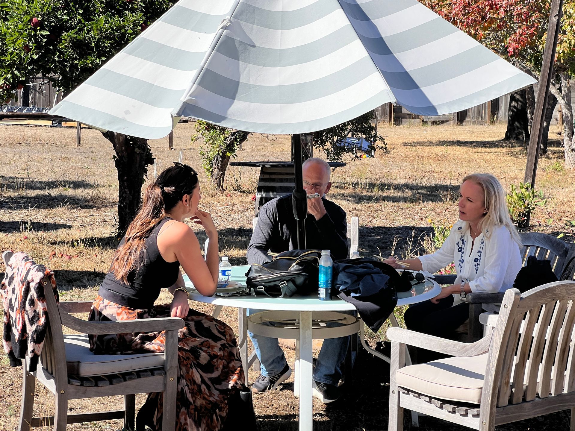 a group of people are sitting at a table under an umbrella and discussing cryotherapy at an event called the cryo ranch 
