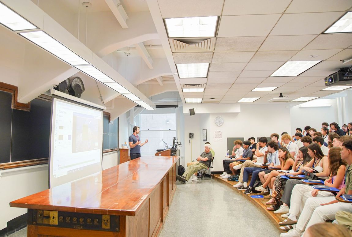 A man is giving a presentation to a large group of people in a lecture hall.