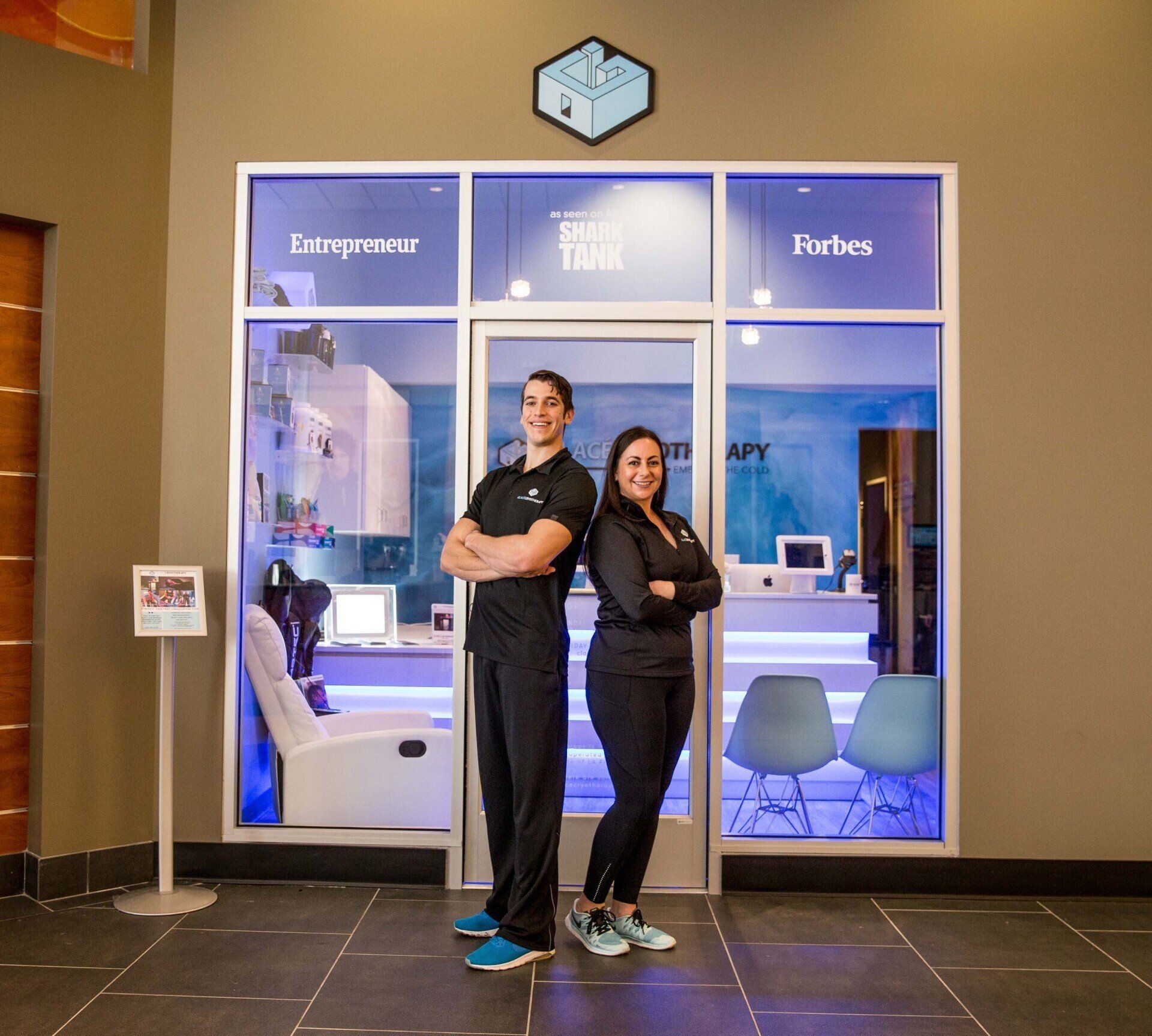 a man and a woman are standing in front of a cryotherapy business in the Bay Area