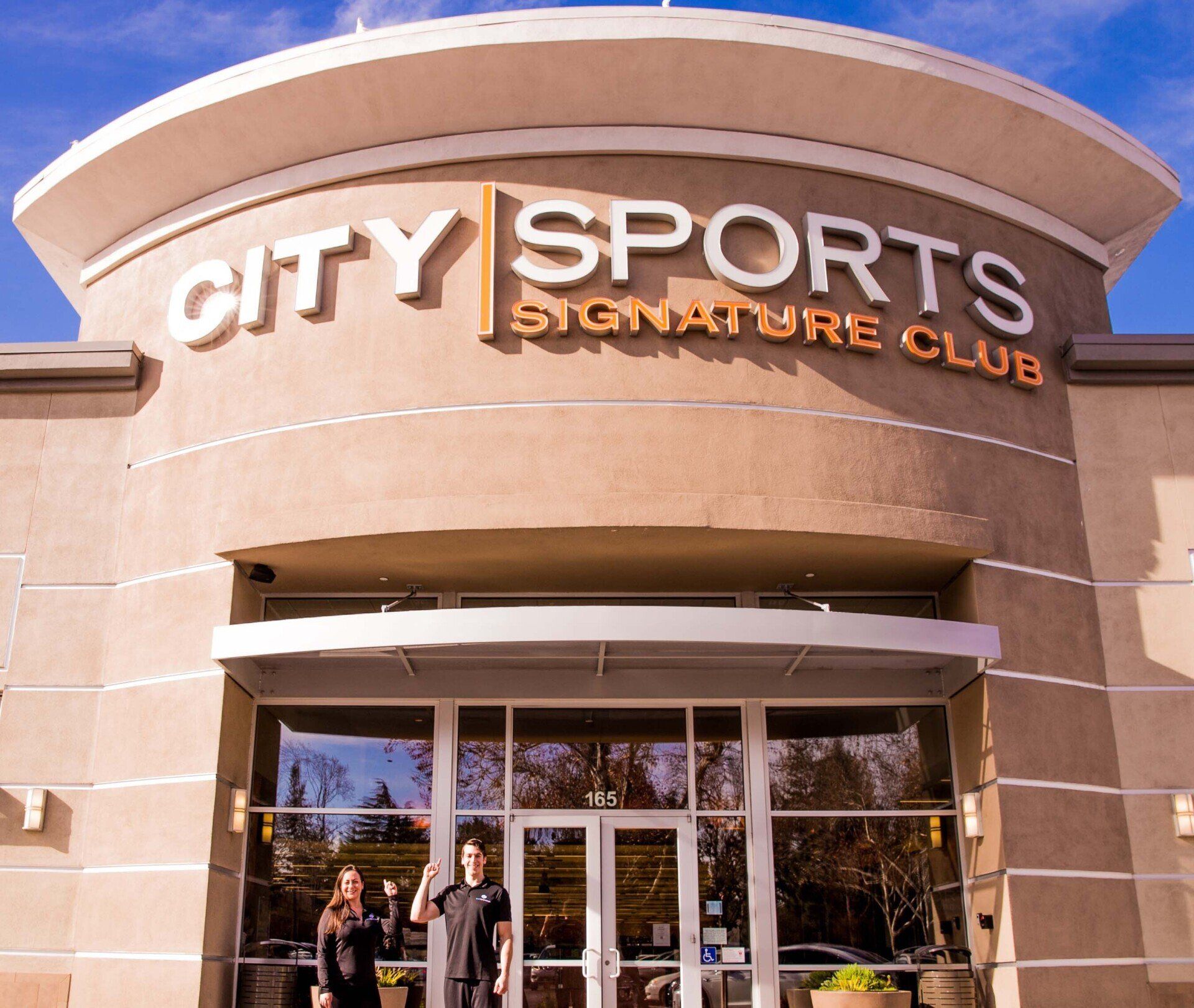 two people standing in front of the city sports signature club where they run a cryo business inside of it 