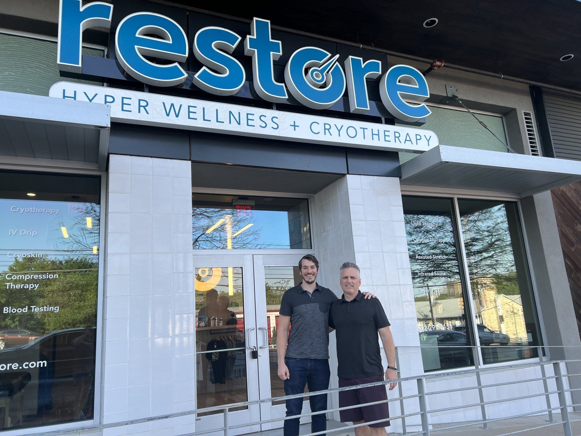 two men are standing in front of a cryo building that says restore