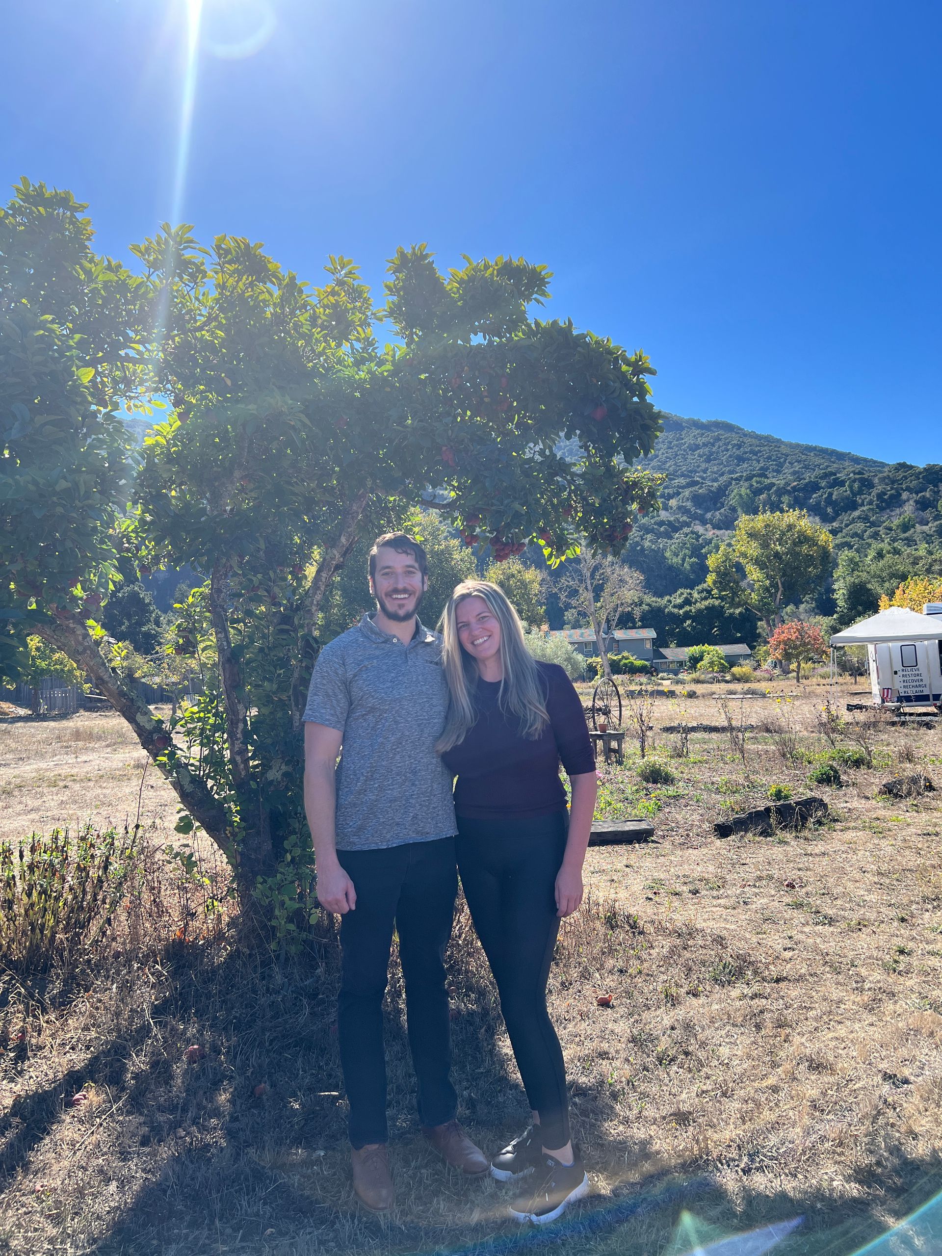 a man and a woman are posing for a picture in front of a tree at a cryotherapy event in California .