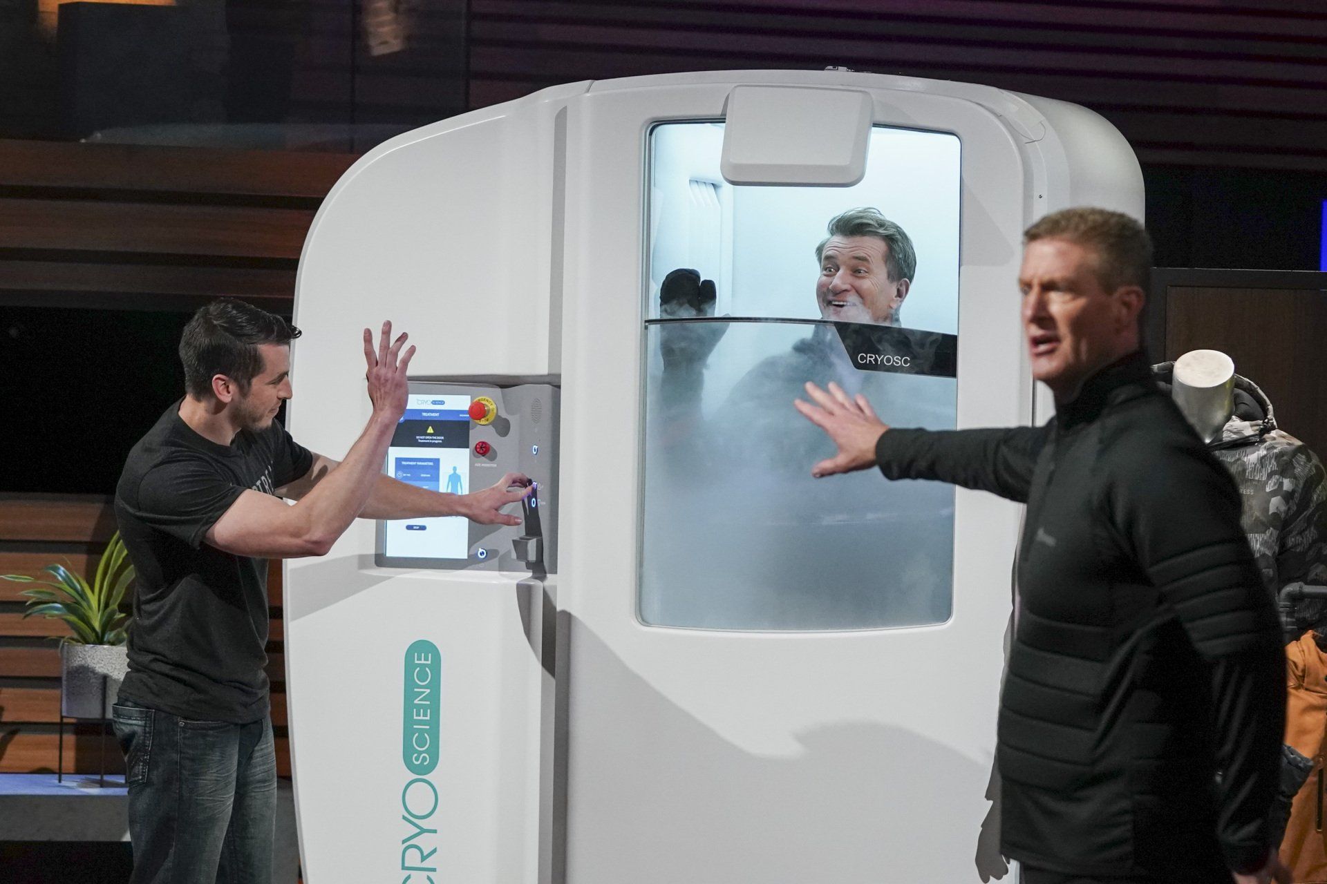 two men are standing next to a cryo machine with a man in it on the tv show shark tank