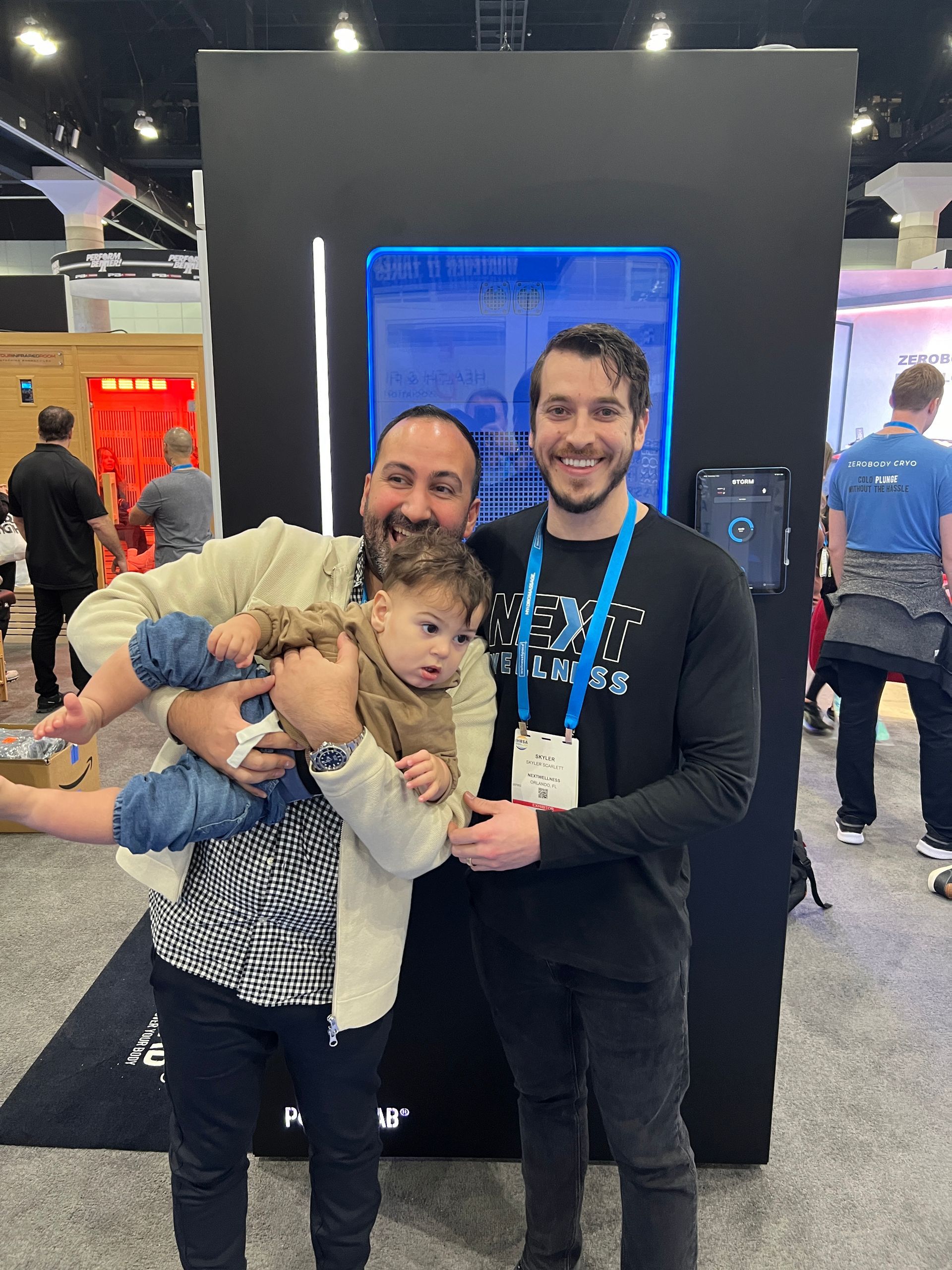 A man is holding a baby in his arms while standing next to two other men.