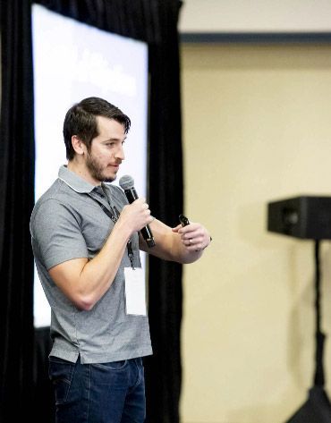 a man is holding a microphone in front of a screen talking about cryo equipment and services .