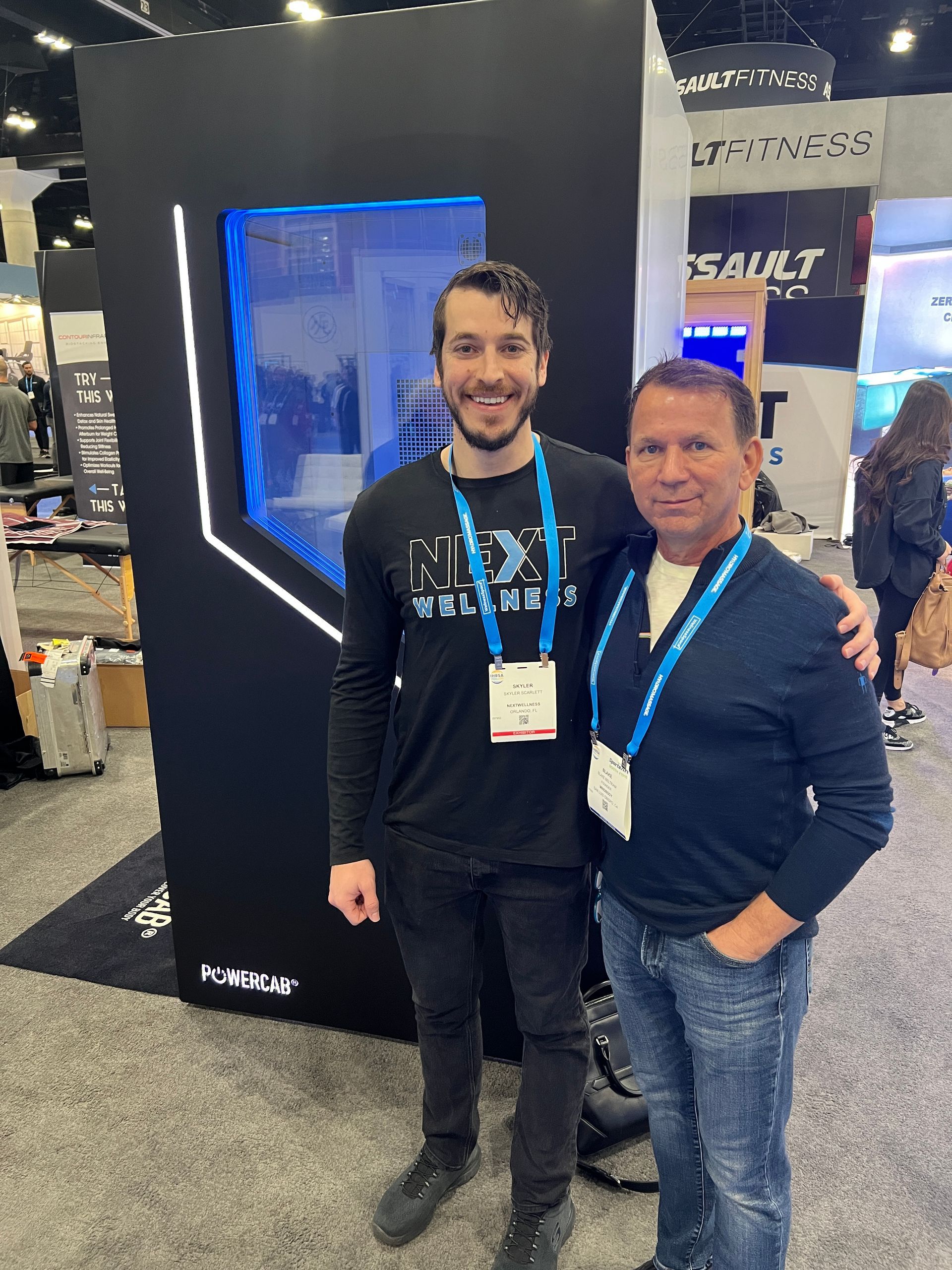 Two men are posing for a picture at a convention.