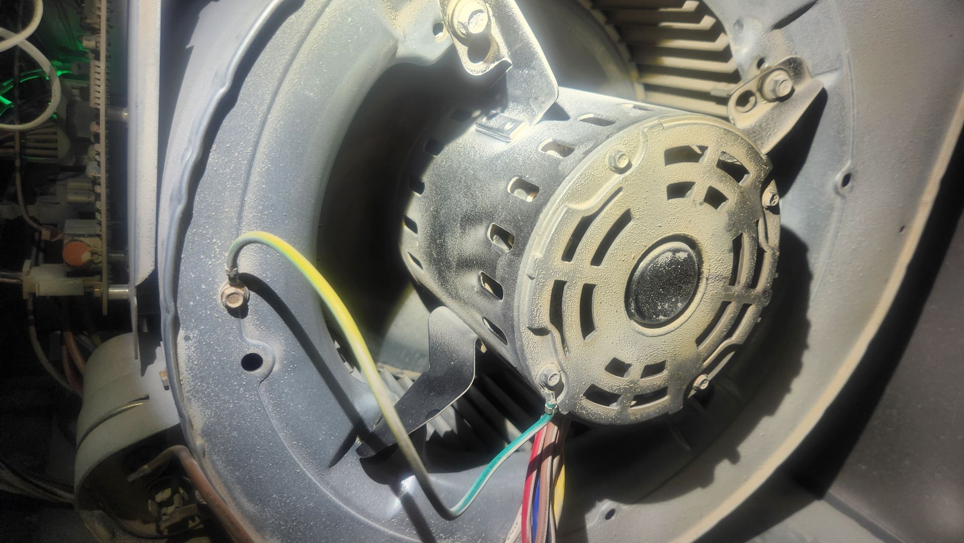 Close-up of a dusty electric motor or blower housing with exposed wires and components inside a machine.