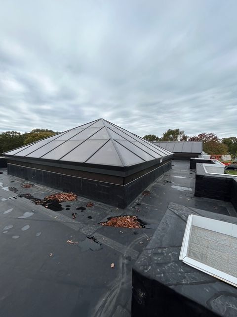 Flat roof with pyramid-shaped skylight. Overcast sky. Debris on the roof surface.