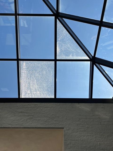 Skylight with a blue sky visible through the glass panels. The glass appears dirty in places.