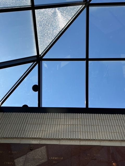 Blue sky visible through a black-framed skylight. Brown brick wall below.