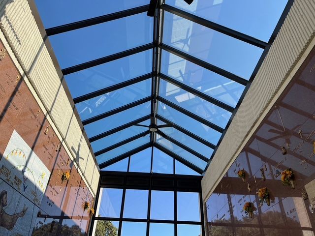 Glass roof of a structure with a view of a clear blue sky; rectangular structure with crypts.