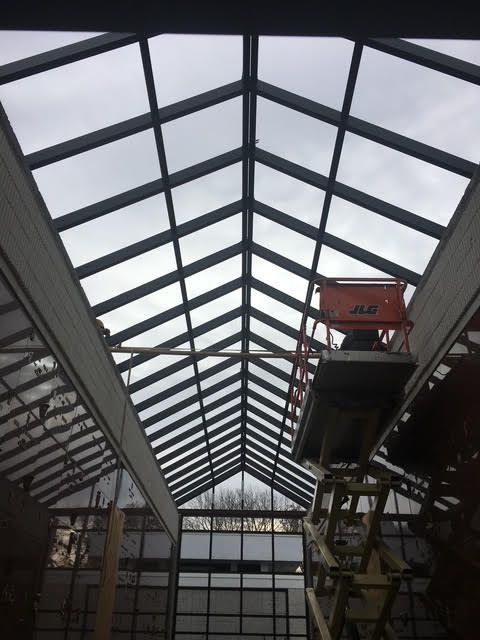 Skylight roof with a scissor lift, against a cloudy sky.