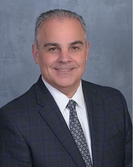 A man in a suit and tie is smiling for the camera