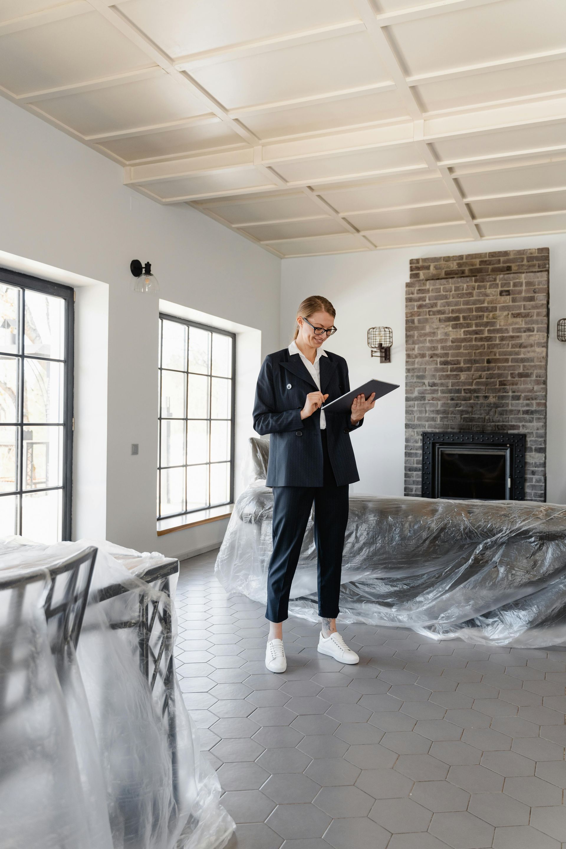 A man in a suit is standing in a living room looking at a tablet.