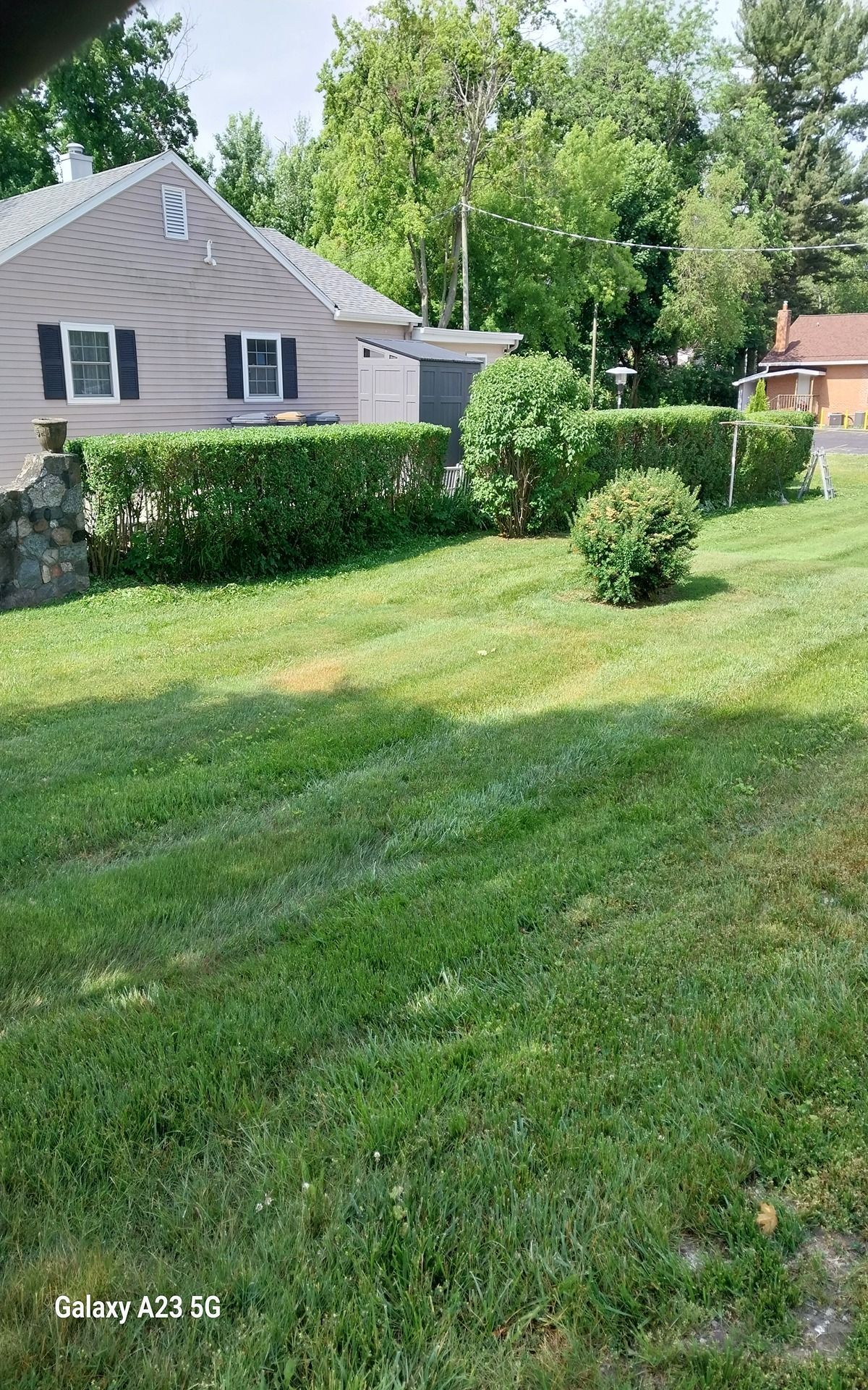 Woman in straw hat smiles, holding wine glass near a lake.