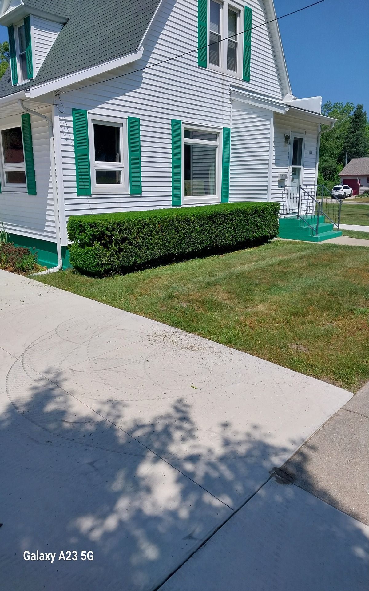 Woman in straw hat smiles, holding wine glass near a lake.